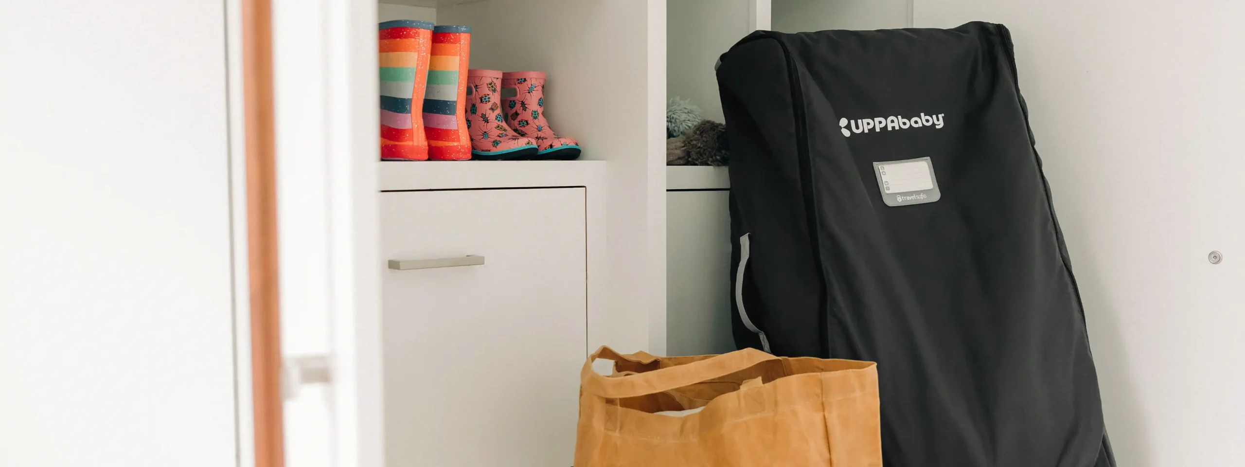 A stroller packed in a travel bag and stored near the door